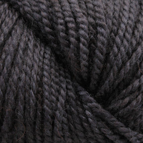 Close-up image of dark charcoal gray Acadia by The Fiber Company yarn wound tightly into a ball. The Fibre Co. (UK) Ltd's yarn has a slightly fuzzy texture with twisted strands that show a mix of lighter and darker fibers, adding depth and variation to the color and creating a subtle tweed effect reminiscent of natural scenic beauty.