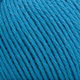 Close-up of bright blue Cotton Fleece from Brown Sheep, tightly wound in a ball. The yarn strands are neatly arranged, showcasing the texture and slight sheen of the fibers. The image highlights the detailed structure and color consistency of the Cotton Fleece, perfect for creating intricate knitting patterns in soft pastels.