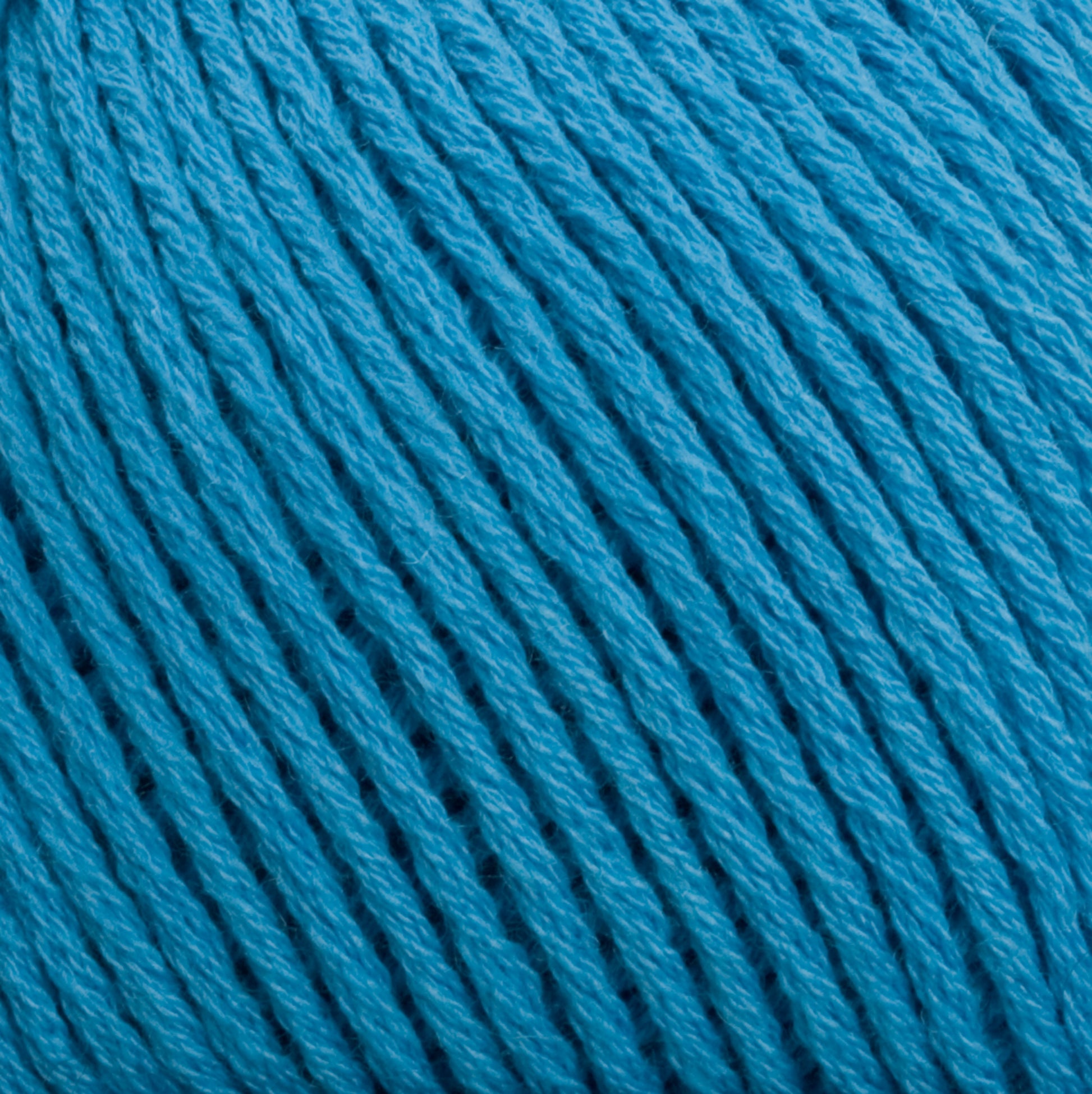 Close-up of bright blue Cotton Fleece from Brown Sheep, tightly wound in a ball. The yarn strands are neatly arranged, showcasing the texture and slight sheen of the fibers. The image highlights the detailed structure and color consistency of the Cotton Fleece, perfect for creating intricate knitting patterns in soft pastels.