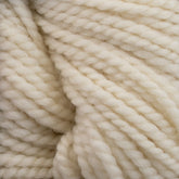 Close-up of thick, cream-colored Norumbega yarn by Caledonian Dye Works, showcasing the textured, twisted strands woven together. Made from 100% U.S. wool, the material appears soft and fluffy with a subtle sheen, creating a cozy and warm impression.