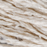 A close-up of a section of Henry's Attic 2-Ply Silk Noil Yarn (Raw Silk) | Mini-cone featuring strands of white mixed with subtle brown patches. The fibers, made from worsted wools, are textured and slightly fluffy, giving the yarn a soft appearance.