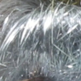 Close-up image showcasing silvery, grey fibers with shimmering highlights from the Clearance! Crystal Mylar Fiber by Foxglove Fiberarts Supply. The fibers reflect light to create a shiny appearance, and the texture is visible with various individual strands standing out against a blurred background.