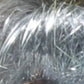 Close-up image showcasing silvery, grey fibers with shimmering highlights from the Clearance! Crystal Mylar Fiber by Foxglove Fiberarts Supply. The fibers reflect light to create a shiny appearance, and the texture is visible with various individual strands standing out against a blurred background.