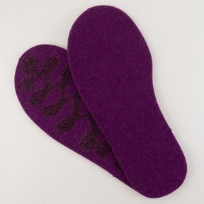 Two violet insoles are placed against a plain white background. The top insole displays a purple pattern on the back, suggesting an anti-slip feature. Crafted with eco-friendly wool, these Joe's Toes Adult's Thick Felt Slipper Soles w/Latex Grip boast a simple, smooth texture.