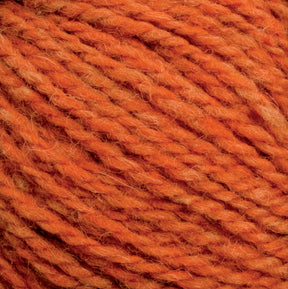 A close-up image of the thick, orange Harrisville Highland - Cones yarn by Harrisville Designs. The texture is visible, showing individual fibers and strands twisted together. The overall color is a warm, rusty orange with subtle variations in hue throughout the unscoured yarn.