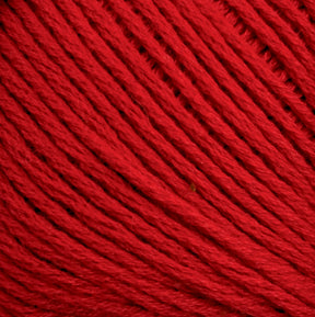 Close-up image of Cotton Fleece yarn by Brown Sheep. The red cotton yarn is densely wound, with individual fibers visible, highlighting its texture and vibrant color—perfect for intricate knitting patterns.