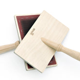 A pair of Kromski Hand Carders by Kromski North America are crossed against a white background. Each carder features a wooden handle and a rectangular, flat surface with red-colored fine metal teeth for carding wool or other fibers.