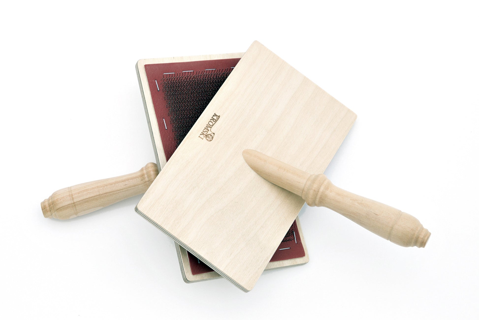 A pair of Kromski Hand Carders by Kromski North America are crossed against a white background. Each carder features a wooden handle and a rectangular, flat surface with red-colored fine metal teeth for carding wool or other fibers.