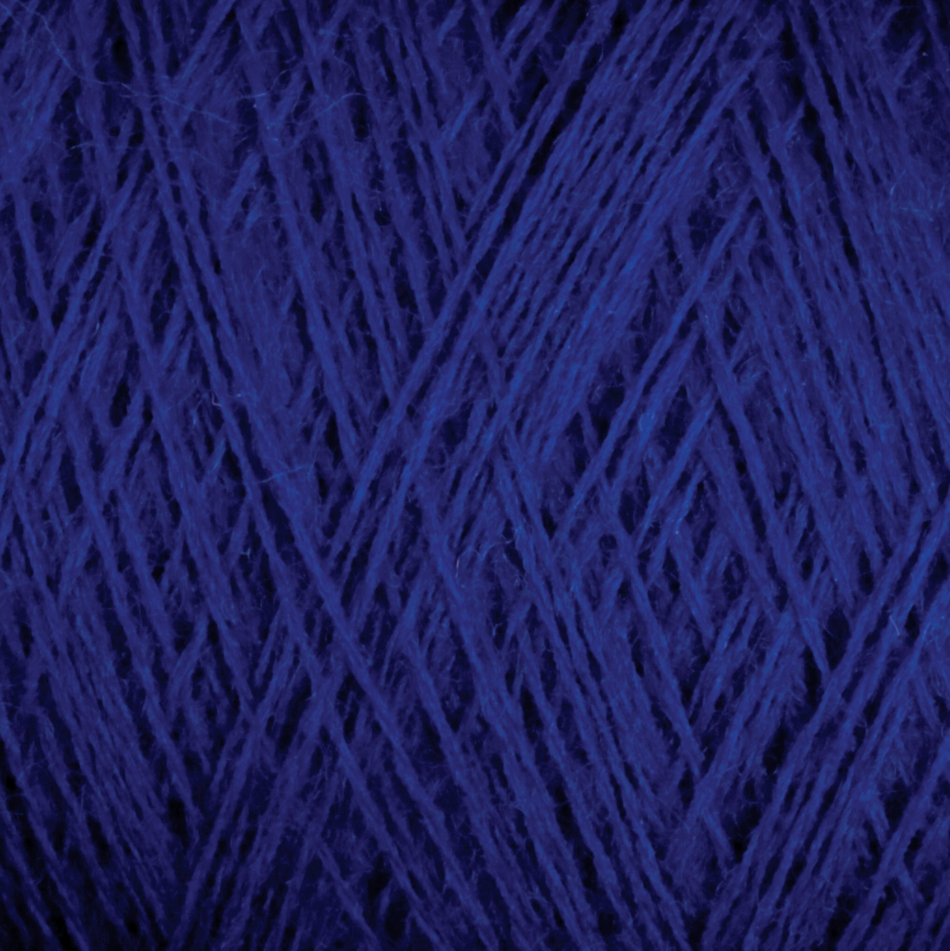 Close-up image of deep blue JaggerSpun Maine Line 3/8 Yarn by Jagger Brothers, Inc., wound into a ball, displaying an intricate crisscross pattern of the strands. The texture appears soft and slightly fuzzy.