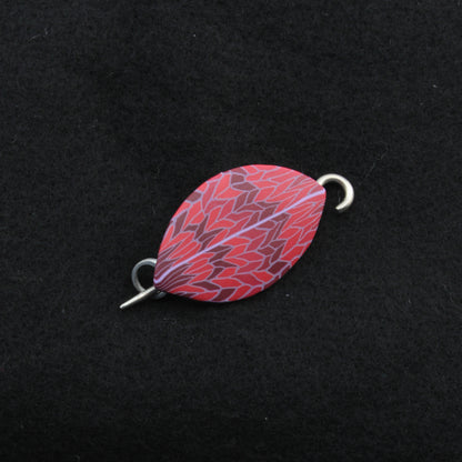 The Leaf Shawl Pin by Bonnie Bishoff Designs features a vibrant polymer clay design with a red and purple abstract pattern, set against a black background, and includes metallic hooks on both ends—ideal for shawl closures or as unique adornments for knit wearables.