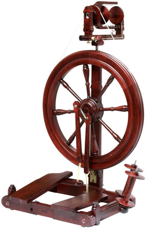 The Kromski Sonata Double-Treadle Spinning Wheel from Kromski North America is a beautifully crafted traditional spinning wheel made in rich, dark wood. It features a large wheel mounted on a sturdy wooden base with dual foot pedals, and various components like the flyer and bobbin are designed for efficiently spinning fibers into yarn. An extra bobbin rests beside the base.