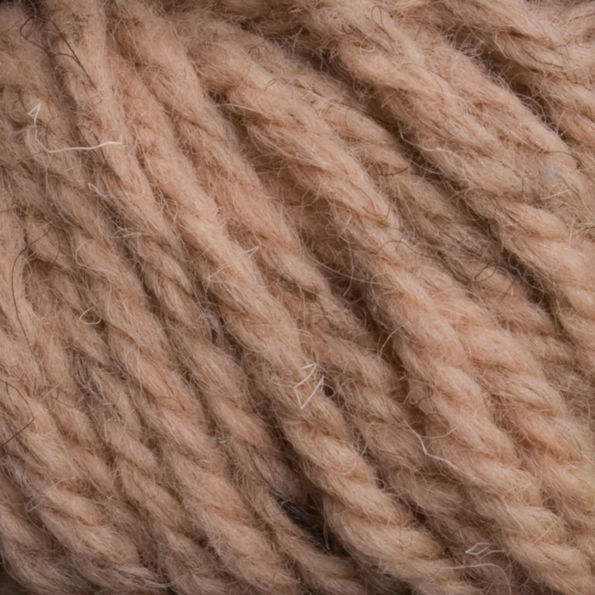 Close-up view of beige, thick, and fluffy strands of Halcyon Yarn Classic Rug Wool | Skein by Caledonian Dye Works wound together into a ball, showing texture and individual fibers—ideal for weavers seeking quality rug wool.