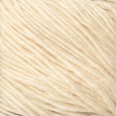 A close-up of Malabrigo Silky Merino, showcasing its cream-colored, soft, and slightly fuzzy texture. The strands are loosely twisted, emphasizing its lightweight and delicate nature. The image highlights the subtle variations in shading within the fibers, showcasing the luxurious quality synonymous with Malabrigo Yarn.