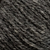 A close-up image of Harrisville Designs' unwashed cone of Harrisville Shetland Yarn in dark grey heather. The fibers are twisted together, showcasing a mix of dark and light grey strands, creating a textured and slightly coarse appearance perfect for Fair Isle knitting designs.