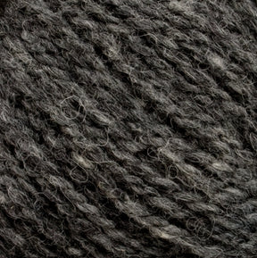 A close-up image of Harrisville Designs' unwashed cone of Harrisville Shetland Yarn in dark grey heather. The fibers are twisted together, showcasing a mix of dark and light grey strands, creating a textured and slightly coarse appearance perfect for Fair Isle knitting designs.