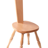 The Ashford Spinning Chair by Ashford Handicrafts Limited is a wooden chair with a tall, narrow backrest featuring a cutout handle at the top. It has three turned legs and a comfortable, round seat that showcases a light New Zealand Beech finish. With its simple and traditional design, the chair is isolated on a white background.