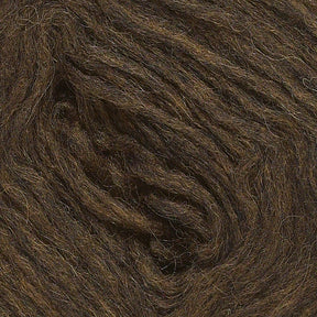 Close-up view of a spool of Berroco, Inc.'s Plötulopi Unspun Icelandic Wool Yarn in dark brown, showcasing its fibrous texture and soft strands coiled tightly together.