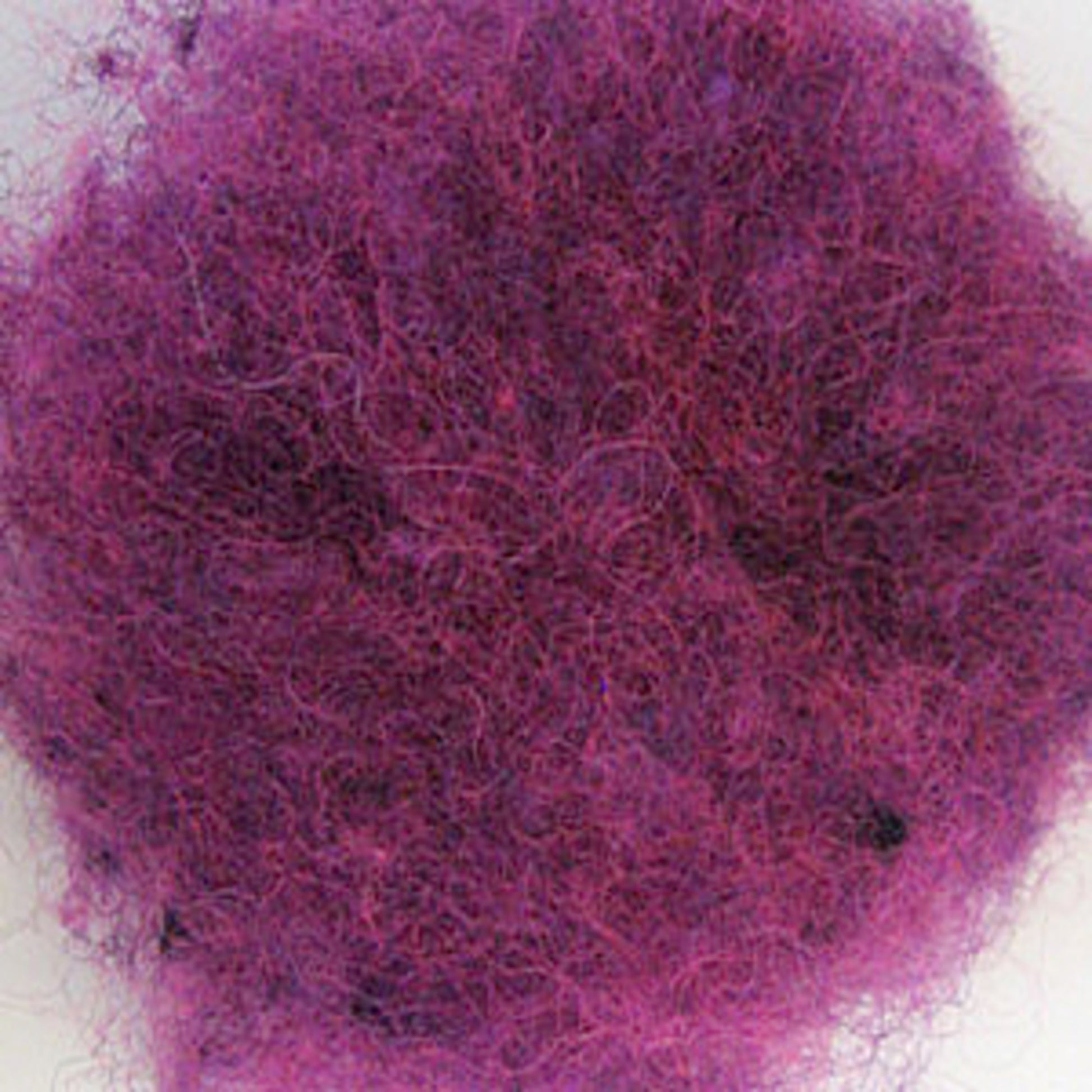 A close-up image of a fluffy, tangled mass of Harrisville Designs' Harrisville Dyed & Carded Wool Fiber in vibrant purple. The texture appears soft and the fibers are closely interwoven, creating a dense and fluffy appearance reminiscent of heathered colors.