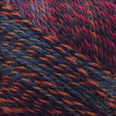 Close-up image of Zauberball Crazy Sock Yarn by Skacel, featuring intertwined strands of red, orange, blue, and black. The texture appears soft, and the color transitions blend smoothly, creating a vibrant and cozy impression ideal for knitting or crafting projects.