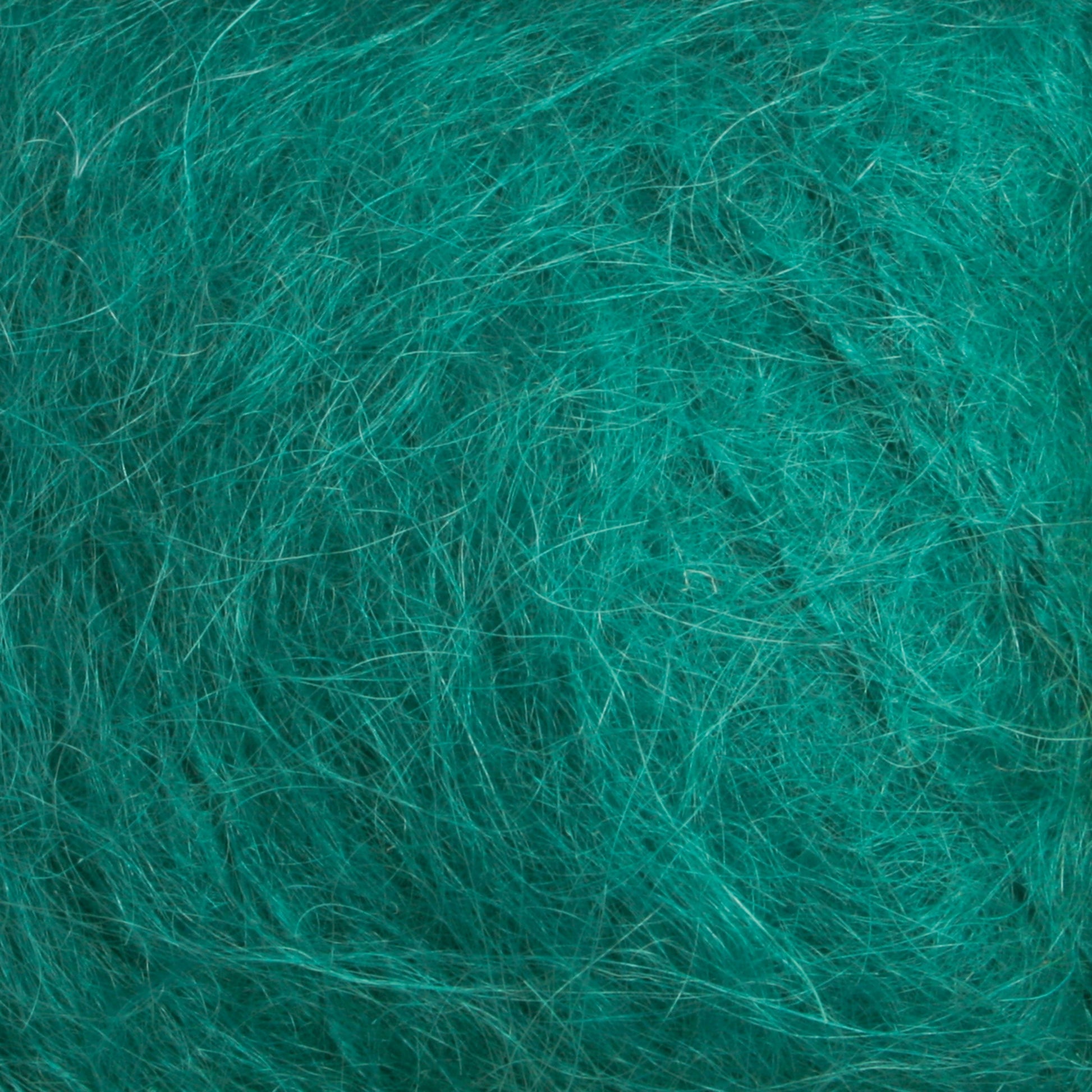 A close-up image showcasing the textured surface of intertwined, fine fibers in a vibrant teal hue from the Victorian Brushed Mohair Yarn by Caledonian Dye Works. The fibers create a chaotic yet soft and fluffy appearance, reminiscent of luxurious mohair or other natural fibrous materials.