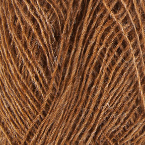 A close-up view of a ball of brown Einband Lopi yarn from Berroco, Inc., showcasing the intertwined strands and texture of the fibers. The yarn appears soft and natural with a slightly rough, fibrous feel, perfect for your next lace knitting project.