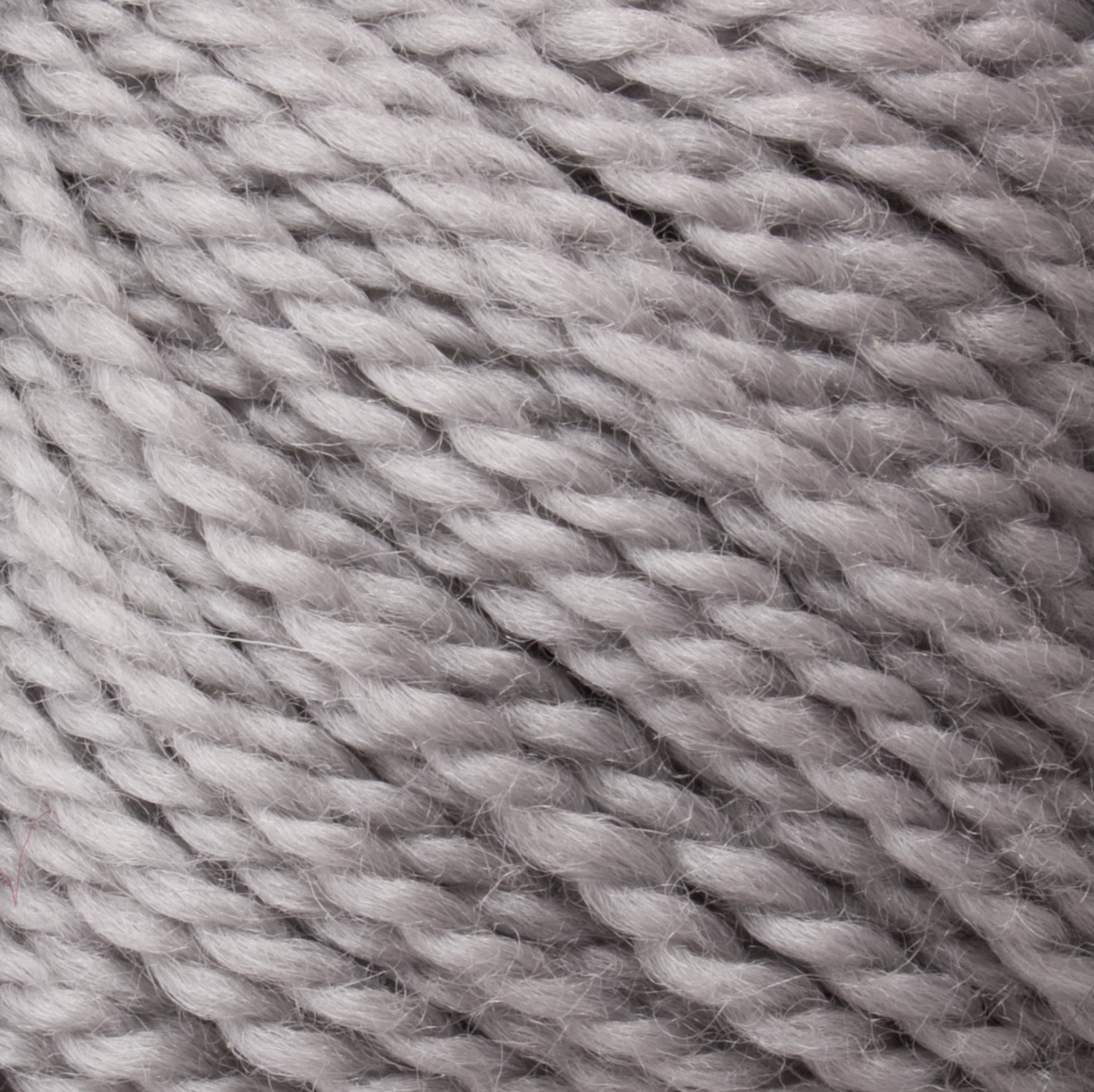 Close-up of Norumbega, a soft, light gray Aran weight yarn ball from Caledonian Dye Works, displaying its twisted and textured fibers. The 100% U.S. wool appears thick and fluffy, ideal for knitting or crocheting cozy items. The individual strands are tightly wound, creating a pattern of subtle, overlapping waves.