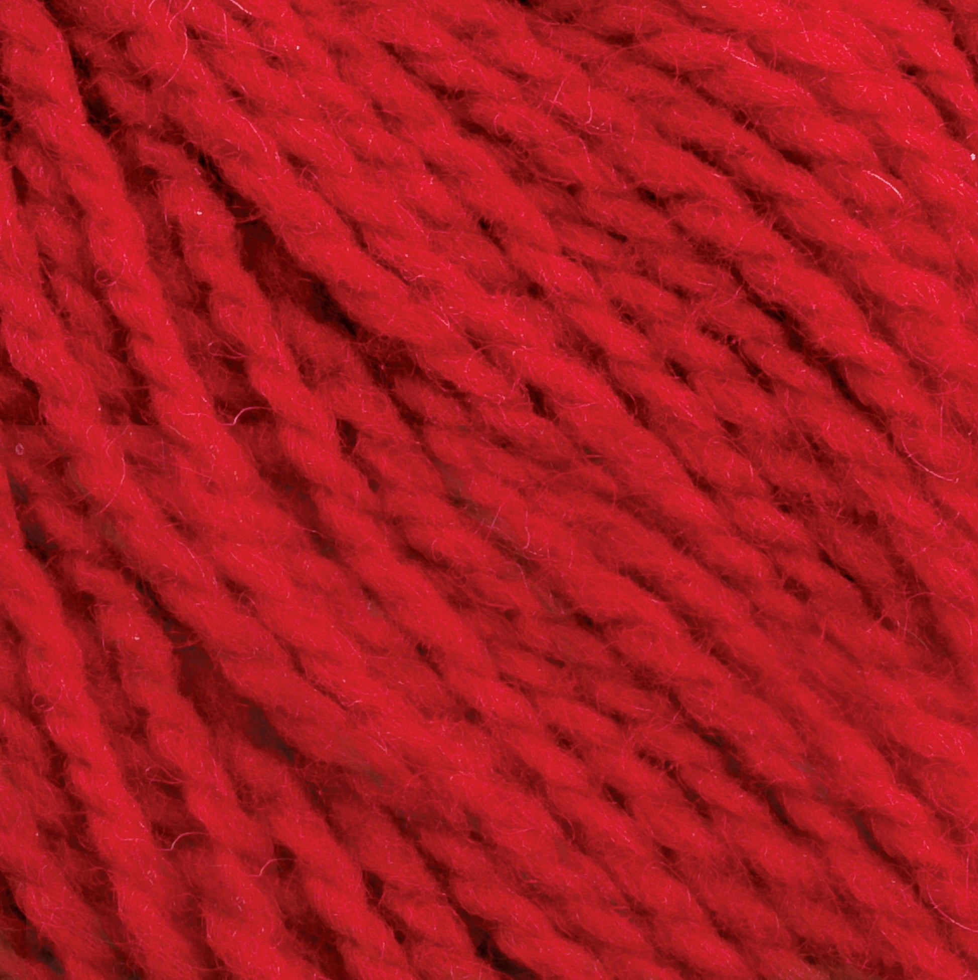 Close-up of red yarn. The yarn strands are tightly twisted and have a soft, fuzzy texture. The image focuses on the intricate details of the Harrisville Designs Harrisville Shetland Yarn - Unwashed Cones fibers, showcasing its vibrant color and texture.