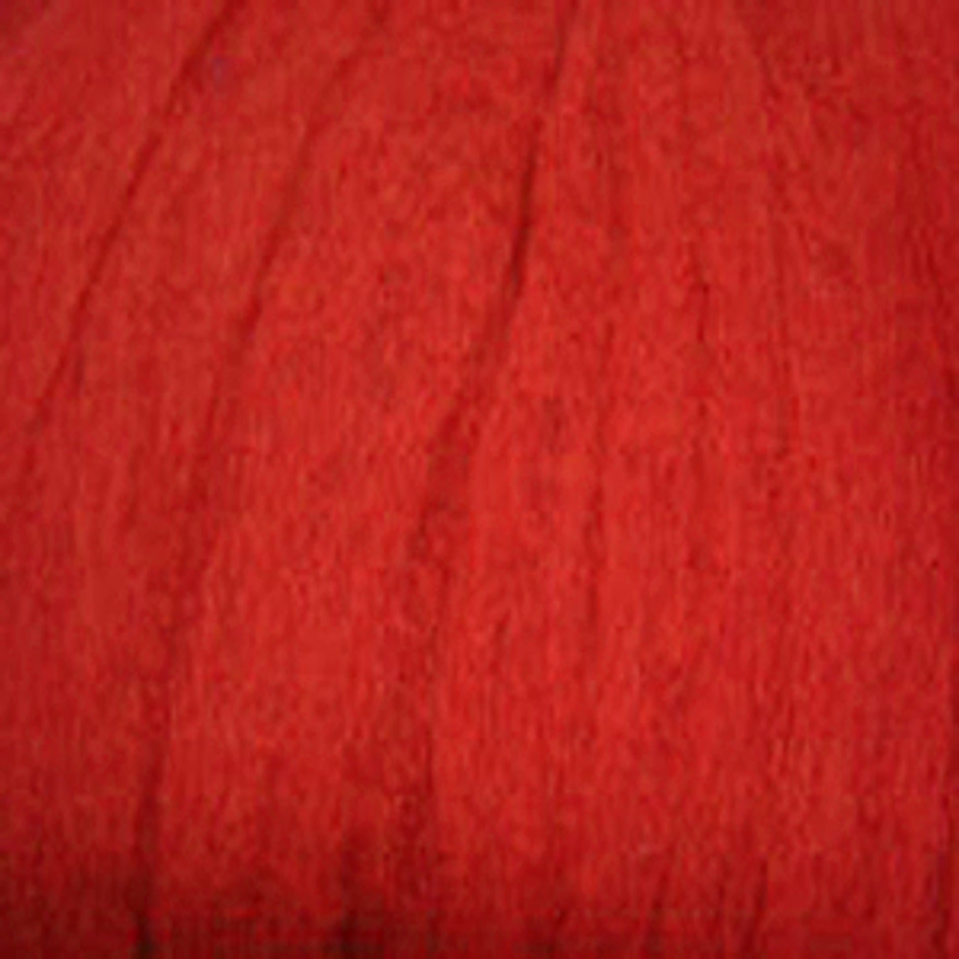 A close-up image of a red textured fabric. The fabric appears soft, with subtle lines and folds creating a sense of depth and variation in the shading of the red color. The texture gives it a Harrisville Dyed & Carded Wool Fiber appearance from Harrisville Designs.