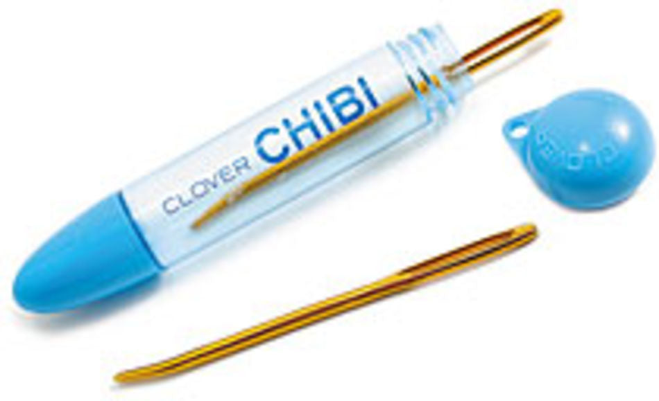 A blue plastic case with "Chibi Jumbo Darning/Tapestry Curved Needles" written on it, from Bryson Distributing, Inc., containing a gold-colored, easy-to-thread needle with a slight curve. The cap of the case is off, lying next to it. Another similar needle rests below the case. Perfect for sweater seaming.