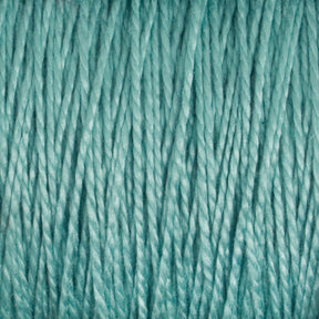 Close-up view of teal-colored 10/2 Pearl Cotton Yarn from Supreme Corp., showing the twisted fibers in a detailed pattern. The yarn appears thick and soft, with a consistent texture throughout the image, highlighting its colorfastness and versatility.