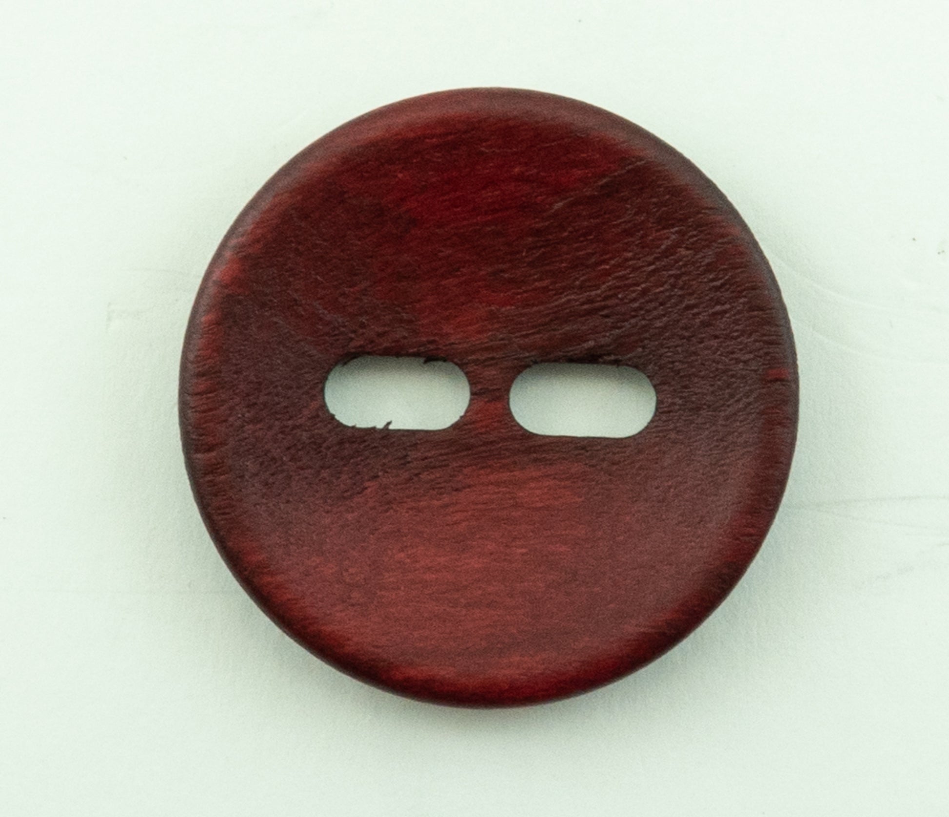 A close-up image of the Buttons Etc. Wood Foxeye button with a 1 3/8" diameter. The two-hole button showcases a slightly rough wood texture, with clear surface details visible, set against a plain, light background.