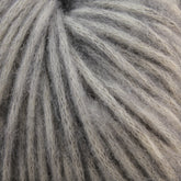 Close-up of Katia Cotton-Merino yarn by Knitting Fever / Euro Yarns, showing a detailed view of its gray and white twisted fibers. The yarn strands are closely packed, creating a textured and soft appearance. The colors blend subtly, showcasing a mix of light and dark shades in this fine cotton-Merino wool blend.