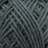 Close-up of a ball of yarn in a soft, muted green color. The Lamb's Pride Worsted Yarn by Brown Sheep reveals its texture, showcasing the individual strands tightly wound together. This image highlights the detail and coziness of the material, making it an ideal choice for felting projects or Navajo-style weaving.