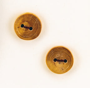 Two handmade "Round or Square Buttons - Mixed Woods" from Favour Valley Woodworking, each featuring two holes and a natural wood grain texture, are placed on a plain light-colored background. The circular buttons also highlight a small central mark, adding to their rustic charm.