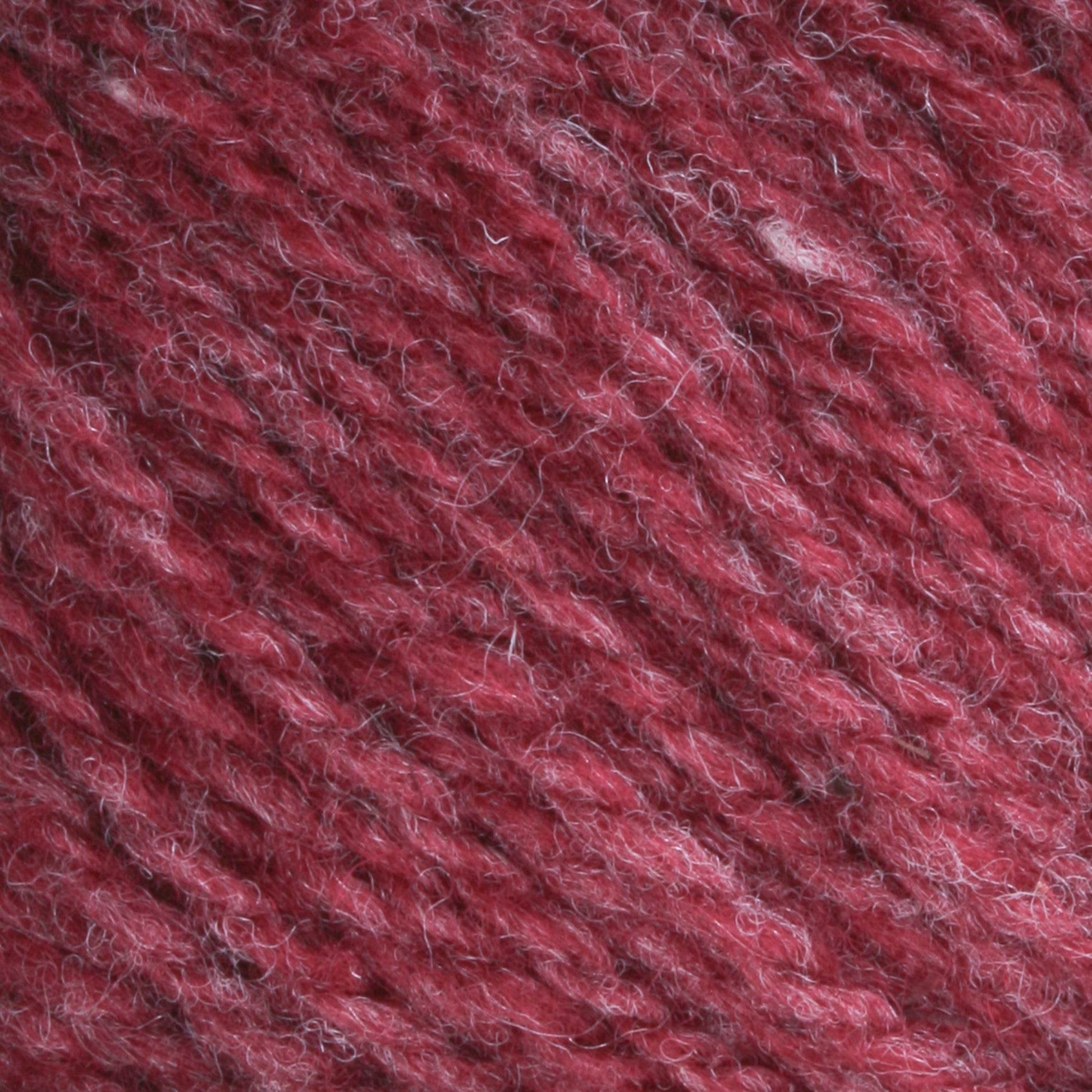 Close-up of strands of red, textured yarn. This Bartlettyarns Maine Wool Yarn, a worsted weight product by Bartlettyarns, features a blend of darker and lighter red fibers that create heathered colors. The texture is soft and slightly fuzzy, with visible intertwined threads.