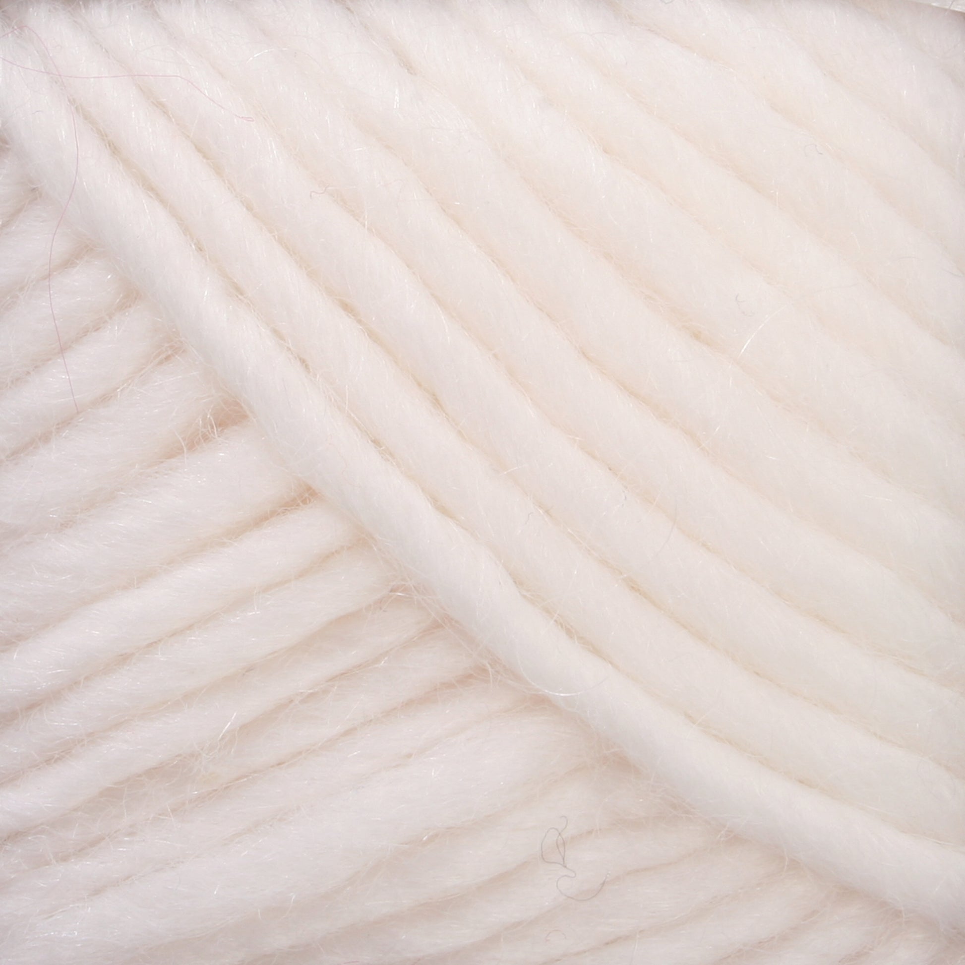 Close-up of Brown Sheep's Lamb's Pride Worsted Yarn, showcasing its soft, thick, off-white strands neatly coiled. The fibers have a slightly fuzzy and smooth appearance, providing a warm and cozy texture. Perfect for felting projects, the yarn features consistent and even thickness throughout.