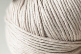 A close-up of a ball of Kingfisher Yarn & Fibre's Jo Sharp Soho Summer DK Cotton with tightly wound fibers, showing detailed texture. The yarn appears soft and smooth, perfect for summer knitting or crocheting projects. The background is blurred, drawing focus to the lightweight cotton yarn.