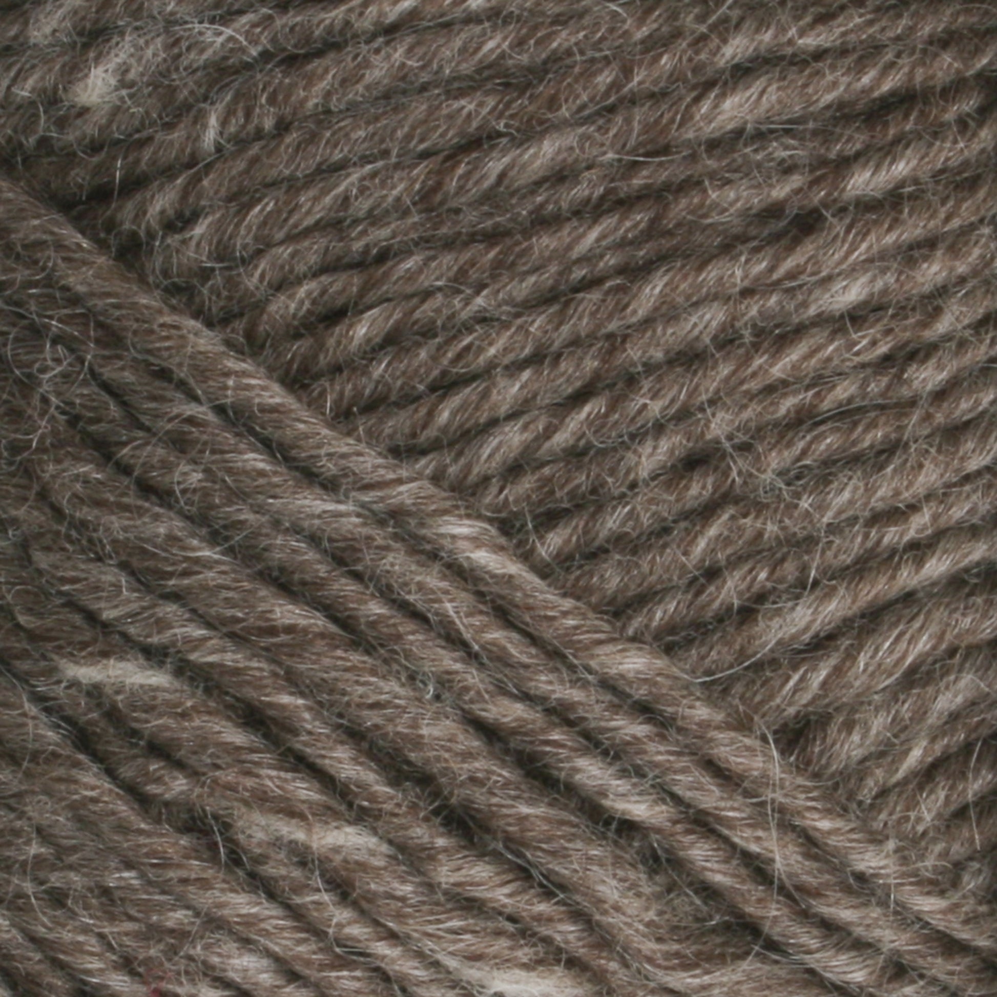 Close-up image of Lamb's Pride Worsted Yarn by Brown Sheep, showcasing tightly spun fibers with subtle variegation in brown and beige. The texture appears soft and slightly fuzzy, making it perfect for felting projects and highlighting the intricate detail in the weave.