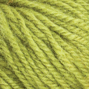 Close-up of the light green Halcyon Deco Rug Wool from Caledonian Dye Works, made from 100% wool with a soft and fuzzy texture. The yarn is tightly twisted and features variations in thickness and color, contributing to its depth and natural appearance. This versatile yarn is perfect for creating unique projects.