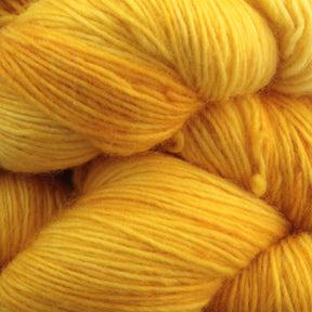 Close-up of several skeins of Malabrigo Lace by Malabrigo Yarn in gradient shades of yellow, ranging from pale to deep golden. The merino wool yarn appears soft and fluffy, with delicate strands tightly wound together. Perfect for knitted shawls, these warm hues create a cozy and inviting texture.