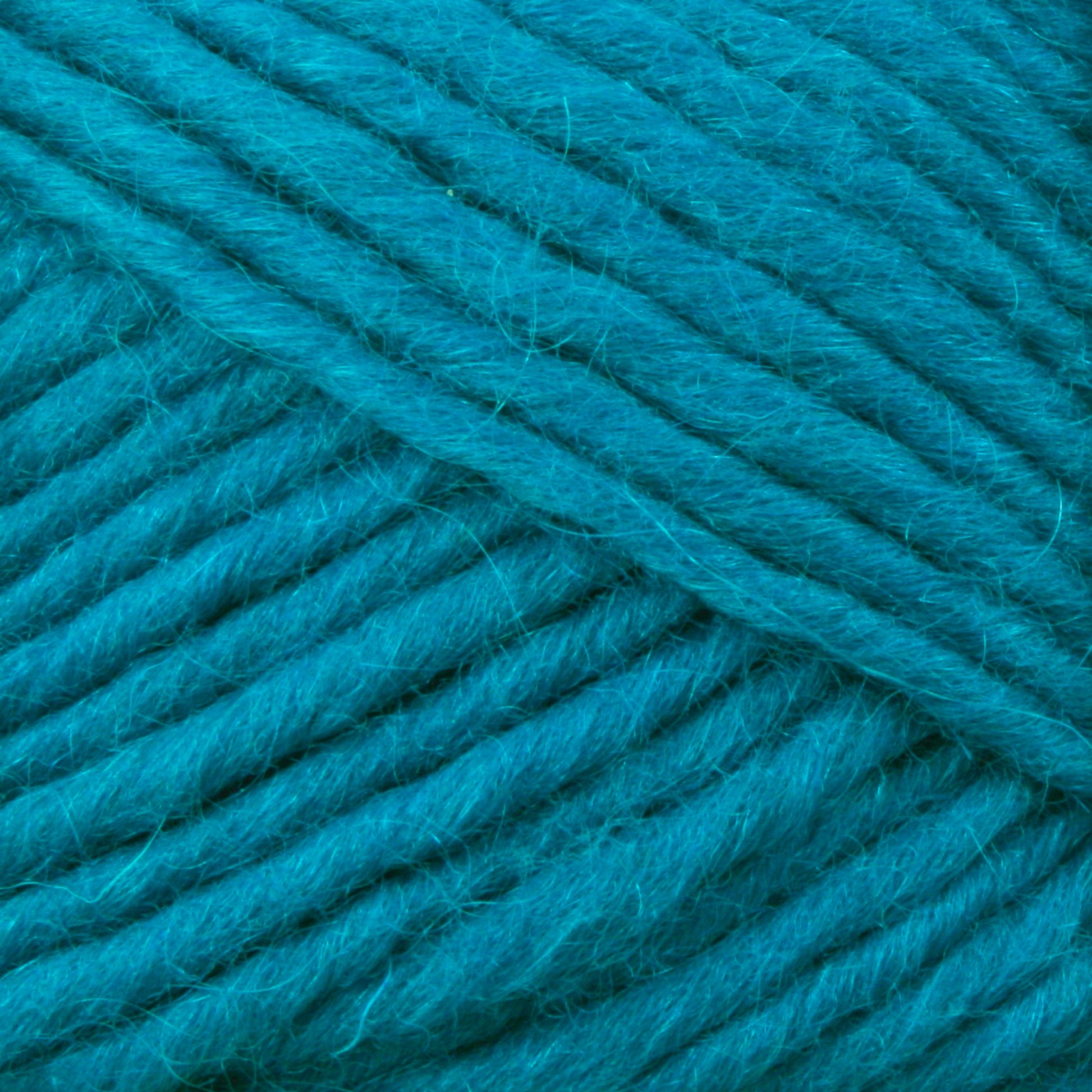 Close-up image of thick, soft Lamb's Pride Bulky Yarn in a vibrant turquoise hue, wound into a skein. The texture of the yarn strands is clearly visible, showcasing the fibers and twists. Perfect for knitters and crocheters, this Brown Sheep yarn promises to add warmth and beauty to Icelandic sweaters or woven blankets.