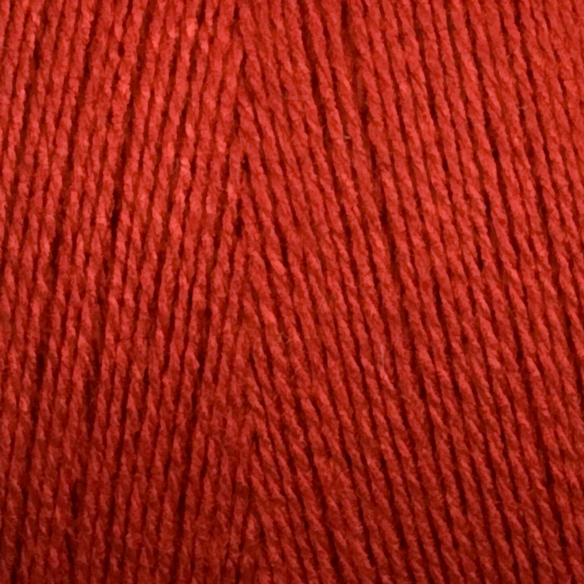 Close-up view of bright red 8/2 Bamboo Yarn from Maurice Brassard, tightly wound into a mini-cone. The texture of the yarn strands is clearly visible, showcasing the smooth and slightly glossy finish of the fibers—perfect for knitters seeking an environmentally friendly option with bamboo yarn's natural allure.