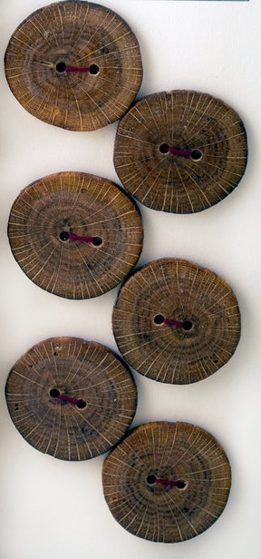 Six round buttons from Favour Valley Woodworking are arranged in an inverted V shape against a white background. Each button features two holes in the center and visible circular wood grain rings. Some of the buttons display dark brown stitching through the holes, highlighting intricate handmade care.