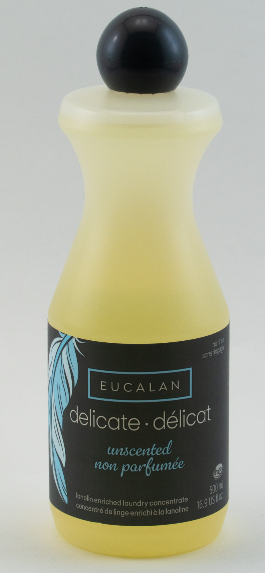 The Eucalan Wool Wash 16.9 oz bottle, enriched with lanolin, features a black label with text in both English and French that reads "delicate - délicat" and "unscented - non parfumée." The yellow bottle, capped with black and adorned with a blue feather design, is also 100% biodegradable.