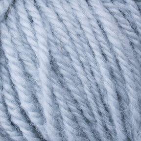 Close-up image of Caledonian Dye Works' Halcyon Deco Rug Wool in a chunky light blue color, highlighting the texture of its twisted fibers. The yarn looks soft and fuzzy, perfect for knitting or crocheting warm garments such as sweaters or blankets. Made from 100% wool, this versatile yarn features a slightly reflective sheen.