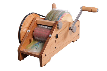 The Ashford Wild Carder by Ashford Handicrafts Limited is a wooden drum carder equipped with a hand crank, metal pins, and a gear mechanism. It features two main drums with closely spaced metal teeth designed for carding wool or other fibers. The construction incorporates both metal and wooden parts, ensuring durability and ease of use.