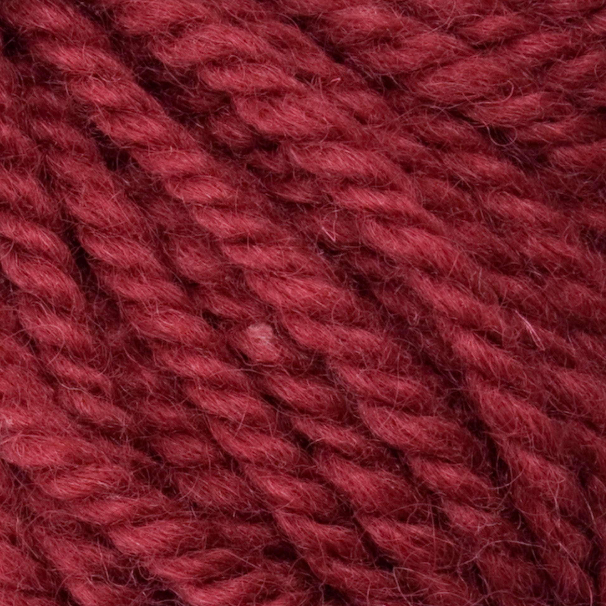 Close-up image of Halcyon Yarn Classic Rug Wool in a deep red hue from Caledonian Dye Works, highlighting its soft, fuzzy texture and tightly woven fibers. The yarn appears thick and hand-dyed, ideal for weavers who want to knit or crochet warm garments and accessories.