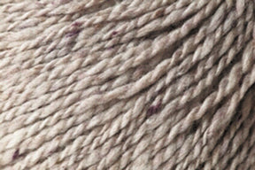 Close-up of a twisted, textured DK weight yarn, primarily light beige with small specks of darker tones throughout. The fibers are tightly spun, showing slight variations in thickness and color, giving it a natural, rustic appearance reminiscent of Jo Sharp Silkroad DK Tweed by Kingfisher Yarn & Fibre.