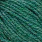 Close-up of Harrisville Designs' Harrisville Shetland Yarn - Unwashed Cones in green, showcasing a spectrum of shades from light to medium and dark green. The yarn has a soft, fluffy appearance with visible individual fibers and a slightly fuzzy texture, making it ideal for creating Fair Isle knitting designs with its harmonious blend of green hues.