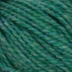 Close-up of Harrisville Designs' Harrisville Shetland Yarn - Unwashed Cones in green, showcasing a spectrum of shades from light to medium and dark green. The yarn has a soft, fluffy appearance with visible individual fibers and a slightly fuzzy texture, making it ideal for creating Fair Isle knitting designs with its harmonious blend of green hues.